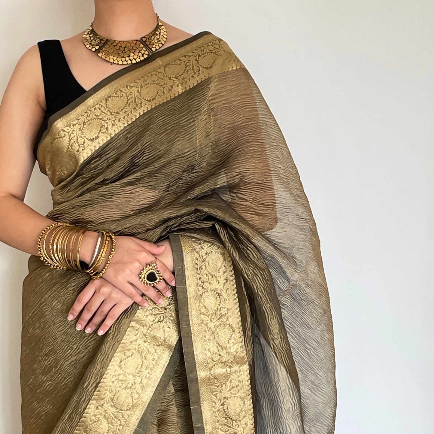 Dark grey crush tissue saree with Banarasi border and golden zari work, Work by Shobhangini. Sophisticated dark grey saree, ideal for evening events.